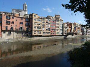 Casas de colores junto al río Onyar en Girona, con el campanario de la catedral asomando por detrás.