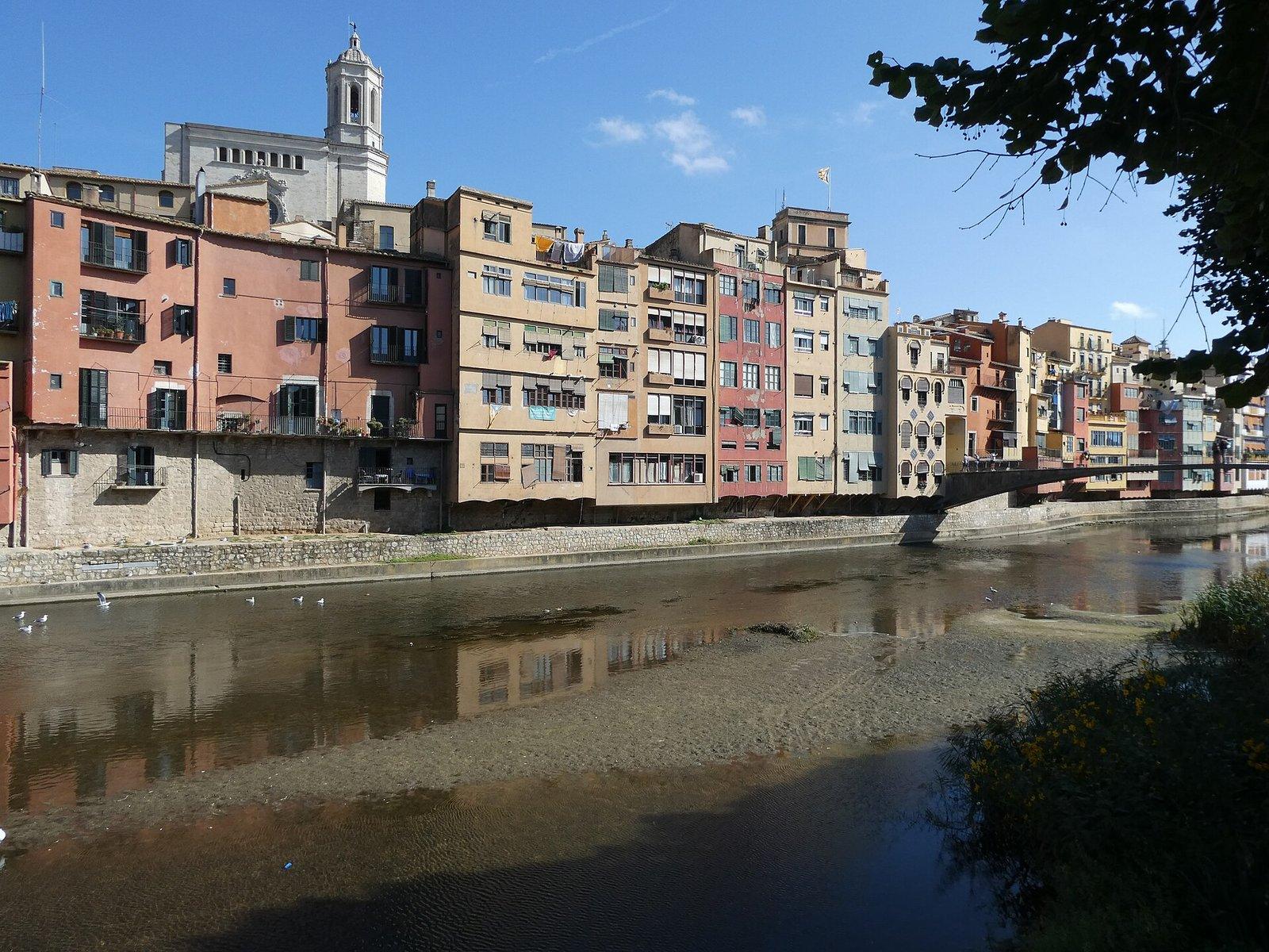 Casas de colores junto al río Onyar en Girona, con el campanario de la catedral asomando por detrás.